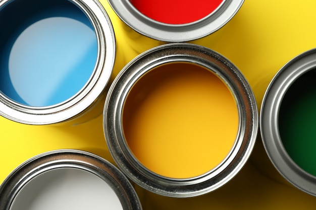 Paint cans on yellow surface and closeup