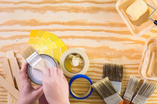 Paint in metal paint can and painters tools on a wood\
board.