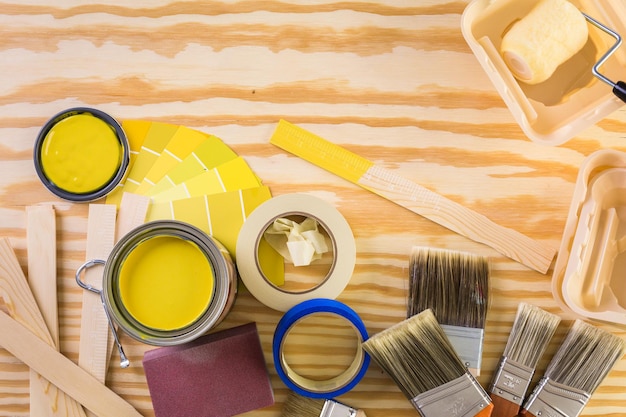 Paint in metal paint can and painters tools on a wood board.