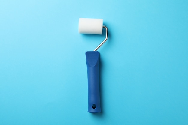 Paint roller on blue background, space for text