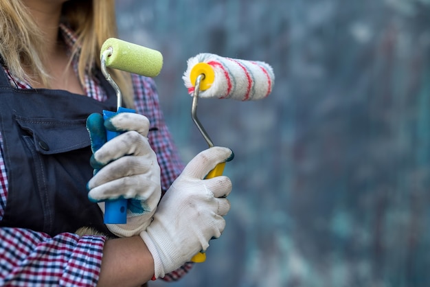 Paint roller in female hand near colorful wall. renovation