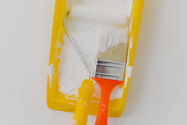 paint roller and paintbrush in tray over white. Refurbishment, repairing and decoration concept.