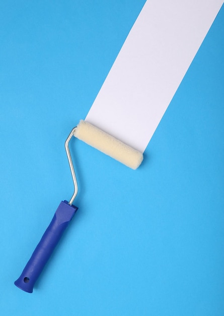 Photo paint roller with white stripe on a blue background home renovation concept