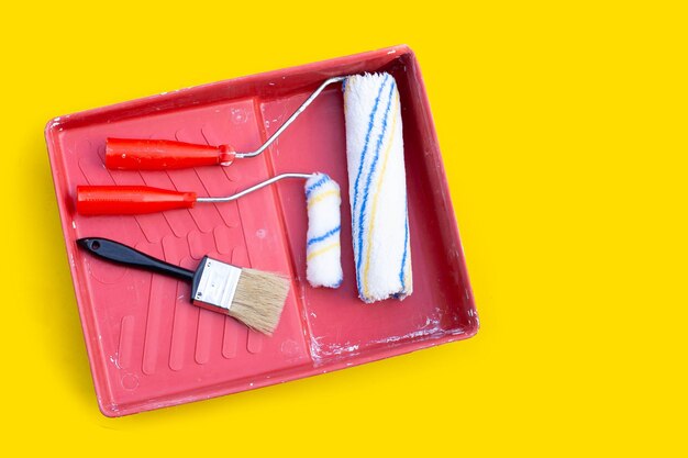 Paint rollers and brush in red paint tray