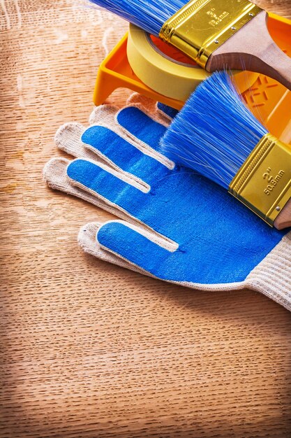 Paint tray brushes duct tape and protective gloves on wood board construction concept