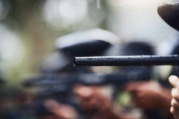 Foto paintball pistool of richten in regen spelletjes arena of teamwerk wedstrijd voor sport uitdaging of militaire training zoom geweer of vat van sluipschutter schietapparatuur voor soldaten leger of slagveld oorlog