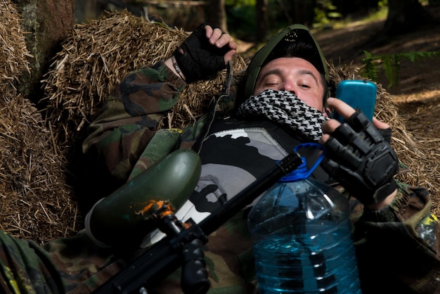 Paintball player resting and looking at the phone