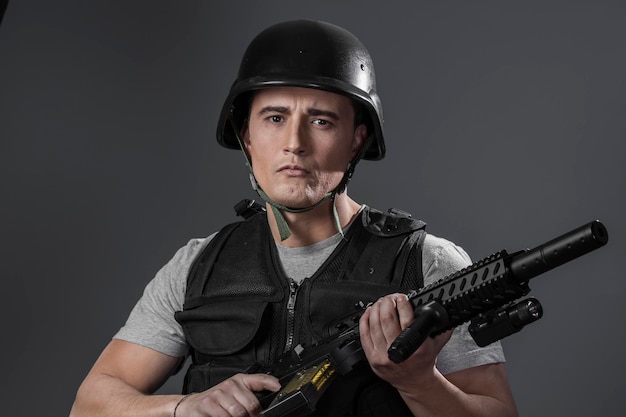 paintball sport speler met beschermende helm gericht pistool, zwart pantser en machinegeweer