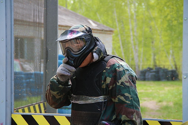 Foto paintball-sportspeler met een beschermend masker gericht op een pistool uit een schuilplaats onder een geweervuuraanval