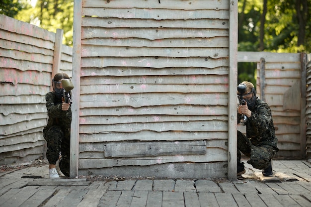 Paintball team shoots with guns from the shelter