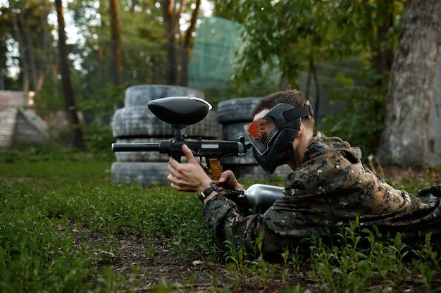 Paintball warrior shoots lying down on the grass