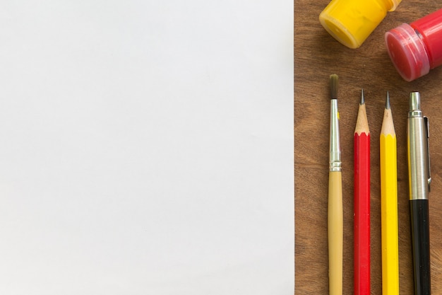 Paintbrush,watercolor,pencil,pen with white paper on wooden table, creative concept.