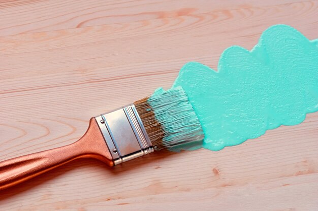 Paintbrush with a gilt pen on a wooden background