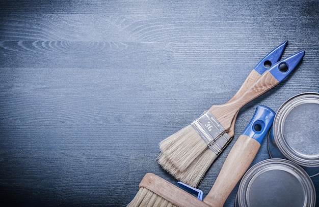 Paintbrushes paint cans on wooden board construction concept