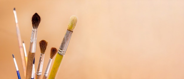 Paintbrushes for paints on an orange background. Panorama. Copy space