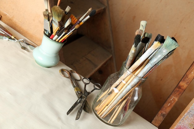 Photo paintbrushes in vases on wooden background