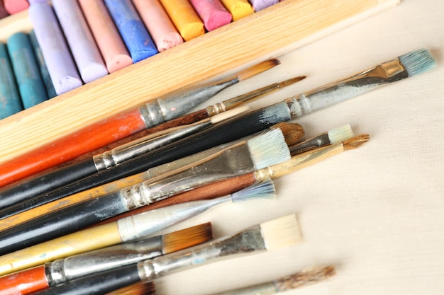 Paintbrushes with colorful chalk pastels in box on fabric background