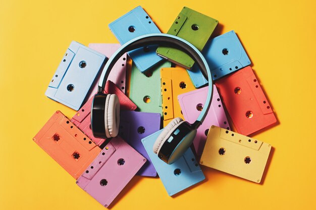 Painted audio cassettes and blue headphones on bright yellow surface