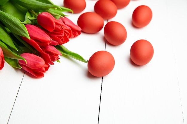 Painted chicken eggs and red tulips on white wooden table Easter Day decor