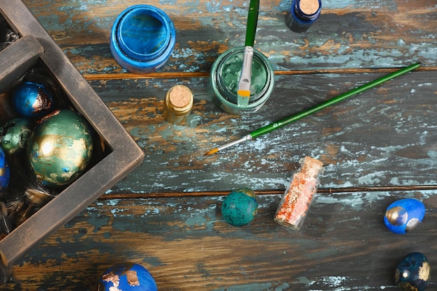 Painted colored Easter eggs in dark wooden box on dark wooden background Boho stile