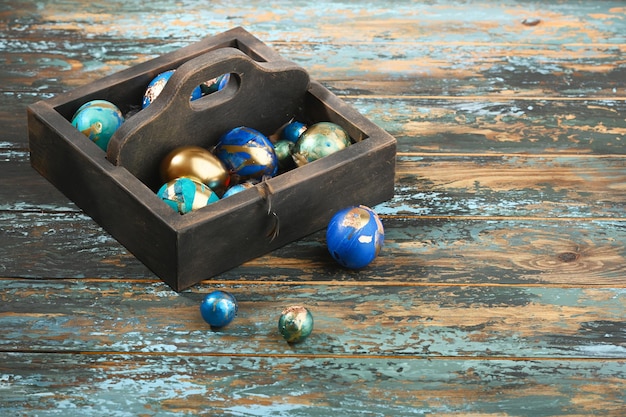 Painted colored Easter eggs in dark wooden box on dark wooden background Boho stile