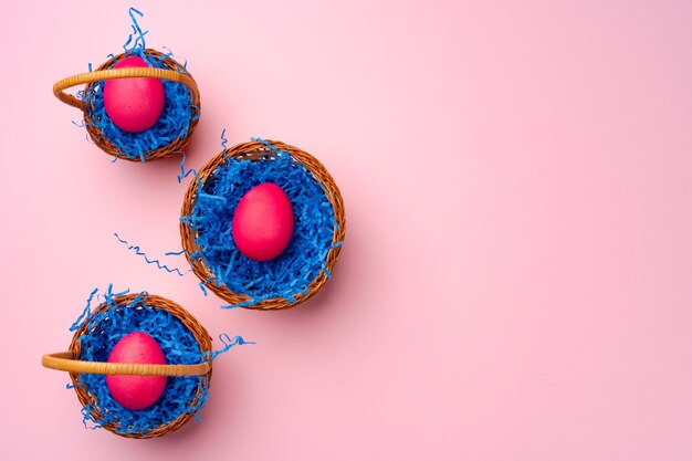 Painted Easter eggs in decorative nest on pink background close up