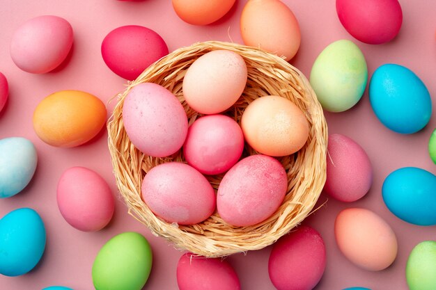 Painted Easter eggs in decorative nest on pink background