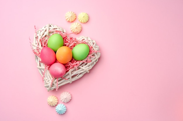 Painted Easter eggs in decorative nest on pink close up