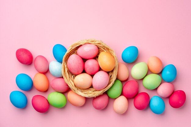Painted Easter eggs in decorative nest on pink close up
