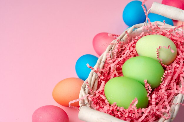 Painted Easter eggs in decorative nest on pink