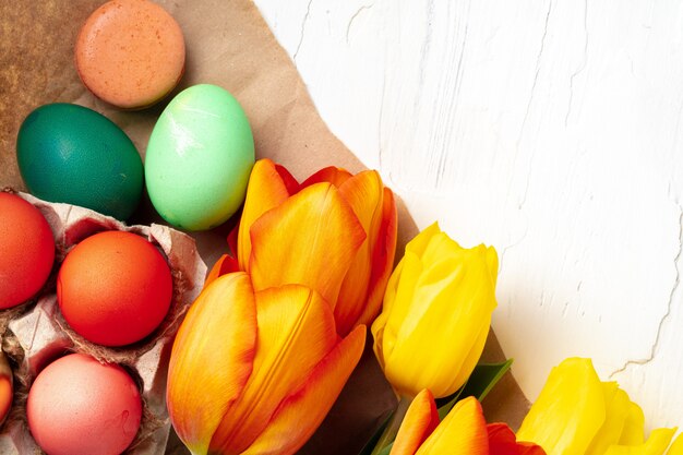 Painted Easter eggs in an eggbox with fresh tulips close up