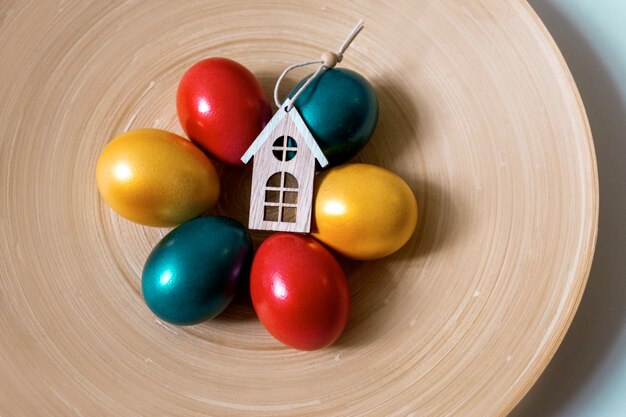 Uova di pasqua dipinte di rosso verde e oro con tre case giocattolo, concetto di vendita di proprietà, vista dall'alto