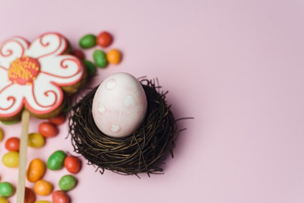 Painted egg for the holiday of light Easter in a nest of branches next to sweets and gingerbread cookies