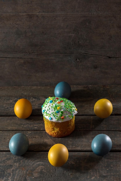 Painted eggs for easter in the colors of the flag of ukraine\
and easter cake yellow and blue cyan on wood texture concept food\
holiday war in ukraine