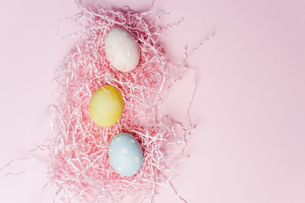 Painted eggs in pastel colors on a pink paper filler and background. Modern easter holiday template