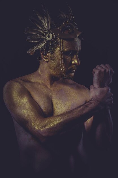 painted golden bodypaint, man with gold helmet, ancient warrior deity