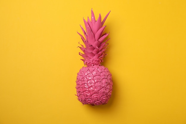 Painted pink pineapple on yellow background, space for text