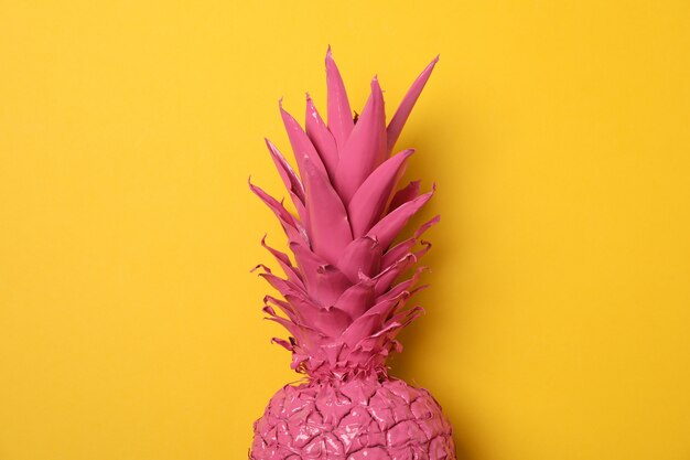 Photo painted pink pineapple on yellow background, space for text