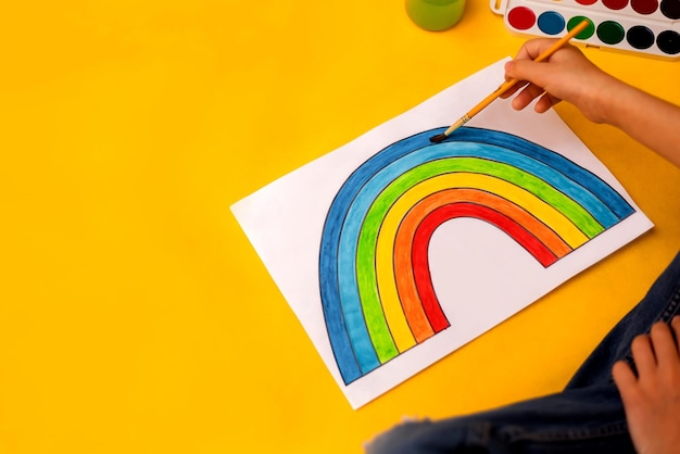 Painted rainbow by the hands of a child on a yellow background