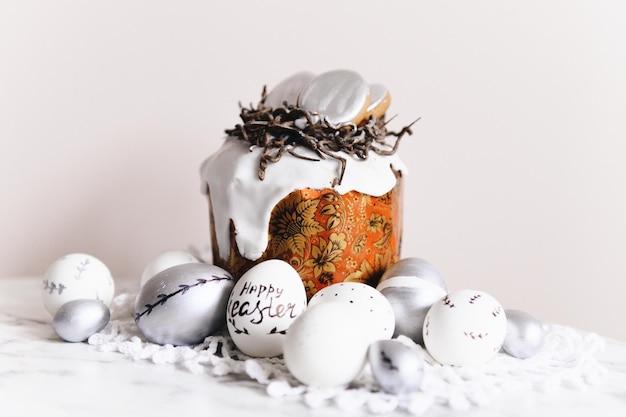 Painted silver and white Easter eggs on a light background and cake postcard free space for text selective focus