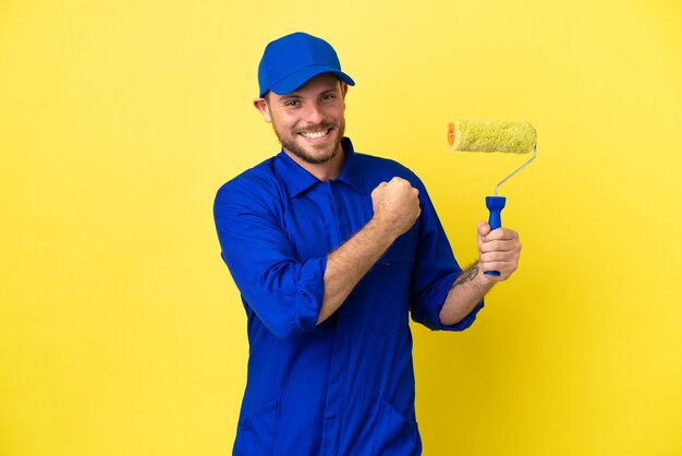 Painter Brazilian man isolated on yellow background celebrating a victory