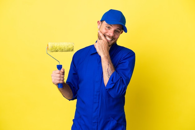 Painter Brazilian man isolated on yellow background happy and smiling