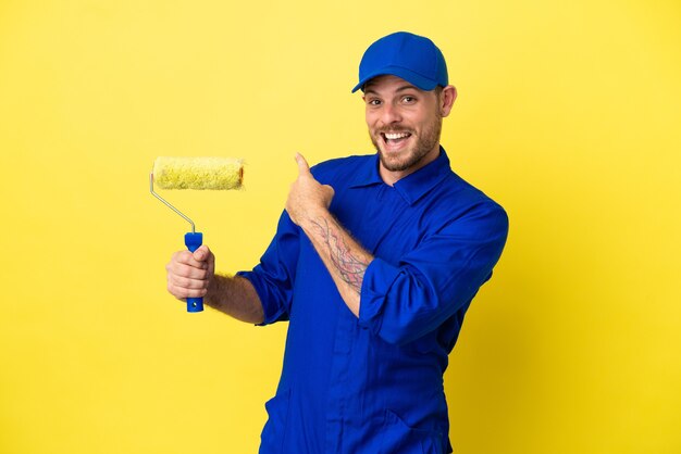 Painter Brazilian man isolated on yellow background pointing back