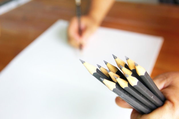 The painter catch black pencils in hand while sketching on white paper