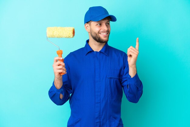 Painter caucasian man isolated on blue background pointing up a great idea