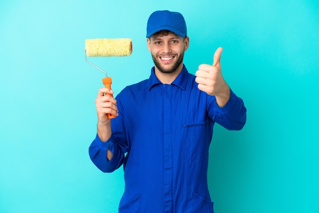 Painter caucasian man isolated on blue background with thumbs up because something good has happened