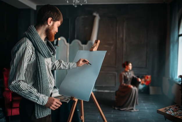 Painter drawing female portrait against easel in art studio. Oil paint