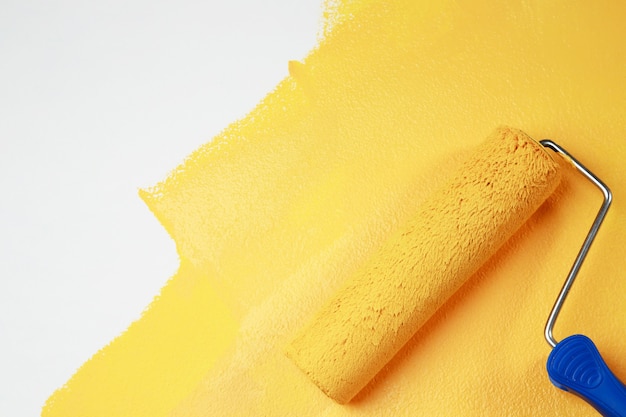 Художник красит внутреннюю стену в желтый цвет