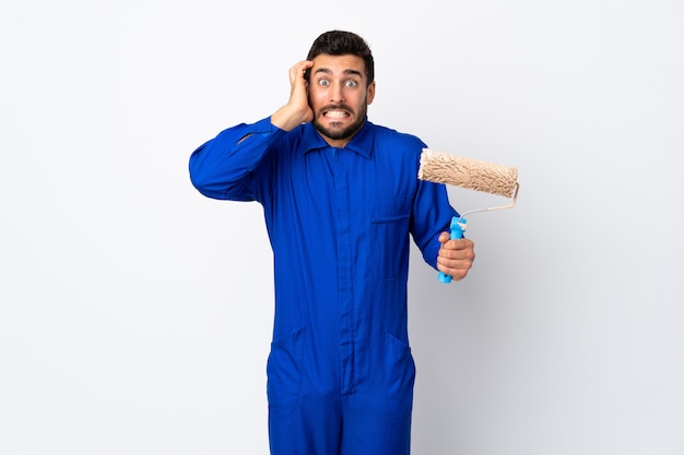 Painter man holding a paint roller isolated on white wall doing nervous gesture