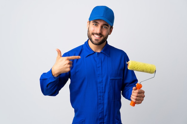 Painter man holding a paint roller isolated on white wall proud and self-satisfied